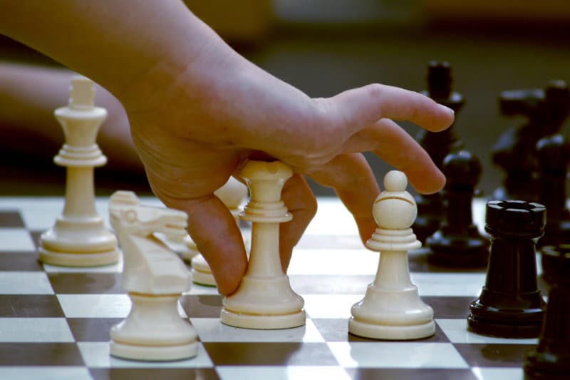Quel jeux d'échec offrir à un enfant ? 2 Un enfant déplace une pièce de jeu d'échecs